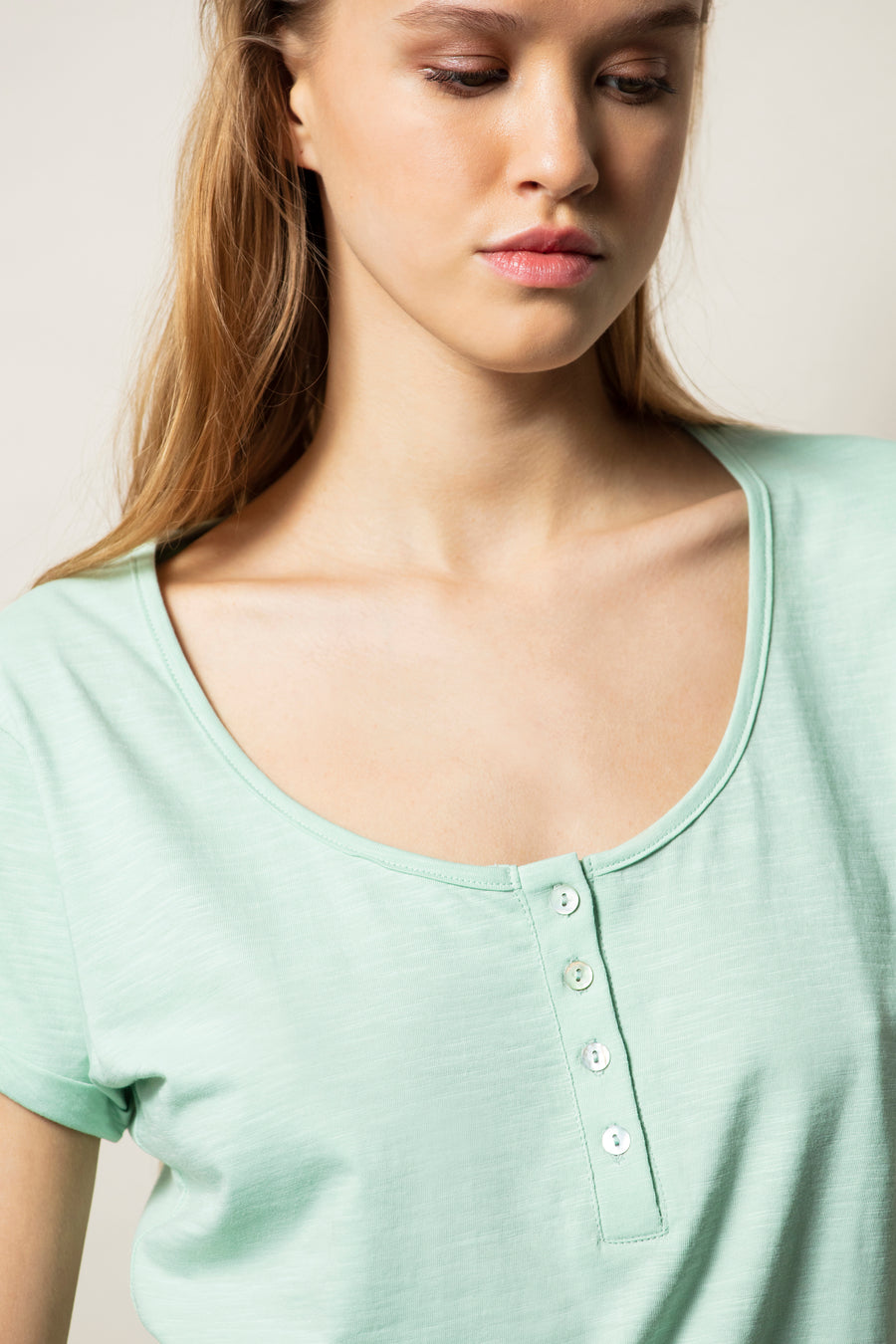 T-shirt básica de decote redondo, manga curta e botões à frente.